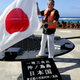 Tokyo Governor Shintaro Ishihara waves the Japanese national flag as he inspects Okinotorishima.